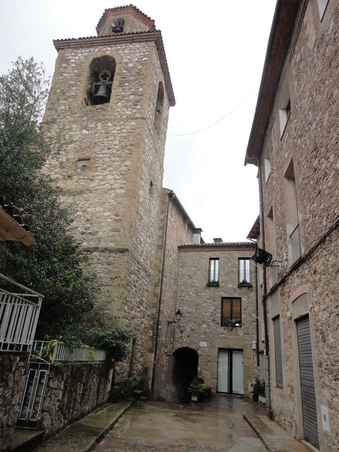 Carrer empedrat al costat d'El Castell de la Pobla de Lillet, amb la torre de pedra al fons
