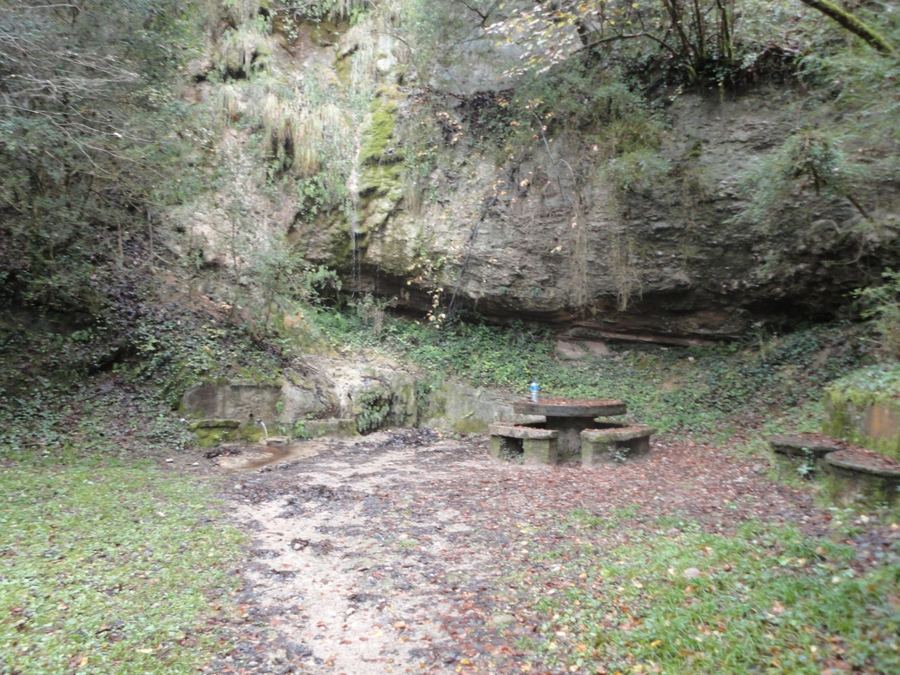 Font de l'Abat con su mesa de piedra bajo la pared de roca, cerca de la Portella