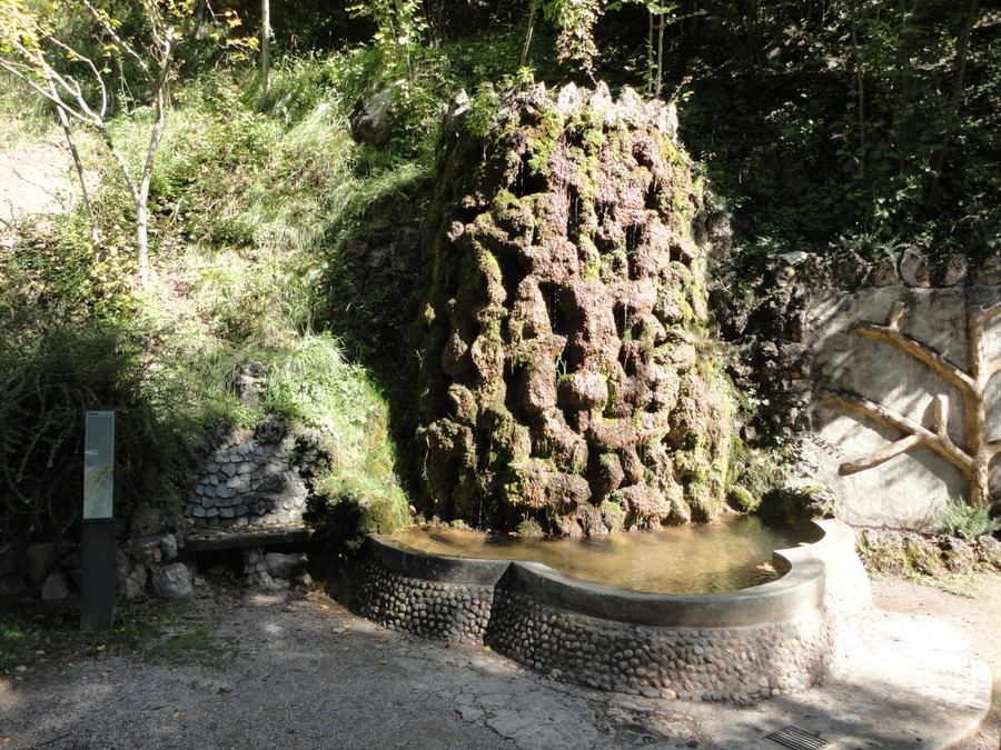 Font dels Jardins Artigas amb l'aigua escorrent per una paret de pedra porosa cap a un estany de còdols