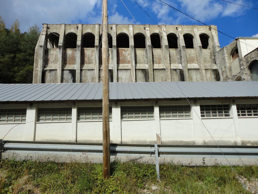 Gran estructura de formigó amb una filera d'arcs de la fàbrica Asland vista des de la carretera