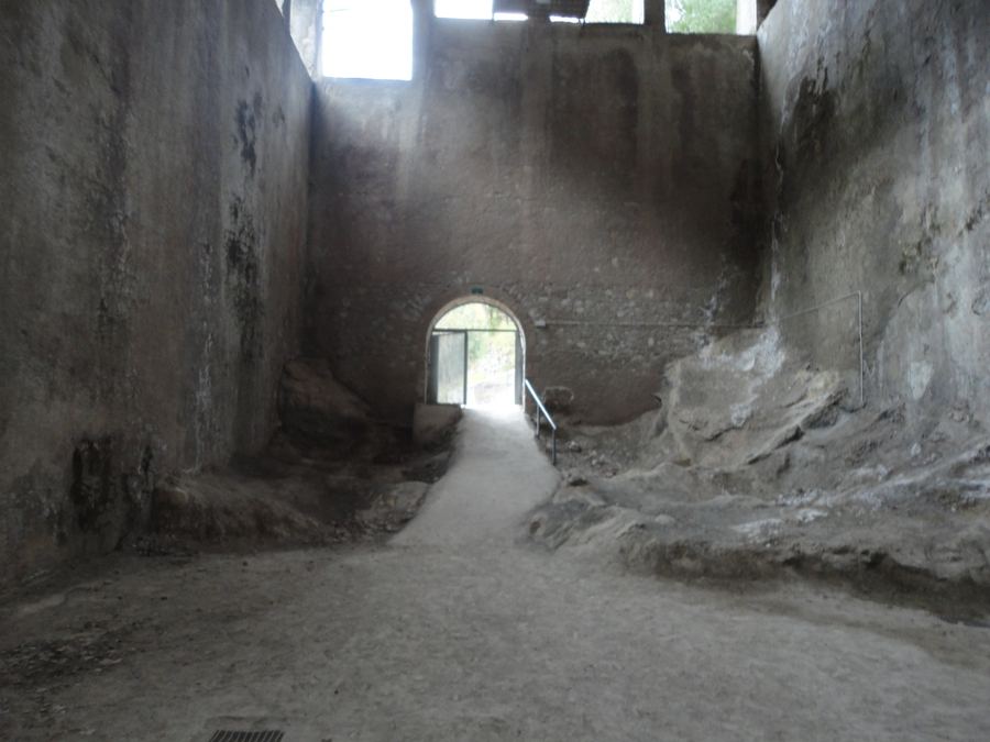 Interior d'una nau de la fàbrica Asland amb murs alts i un camí cap a una porta en arc