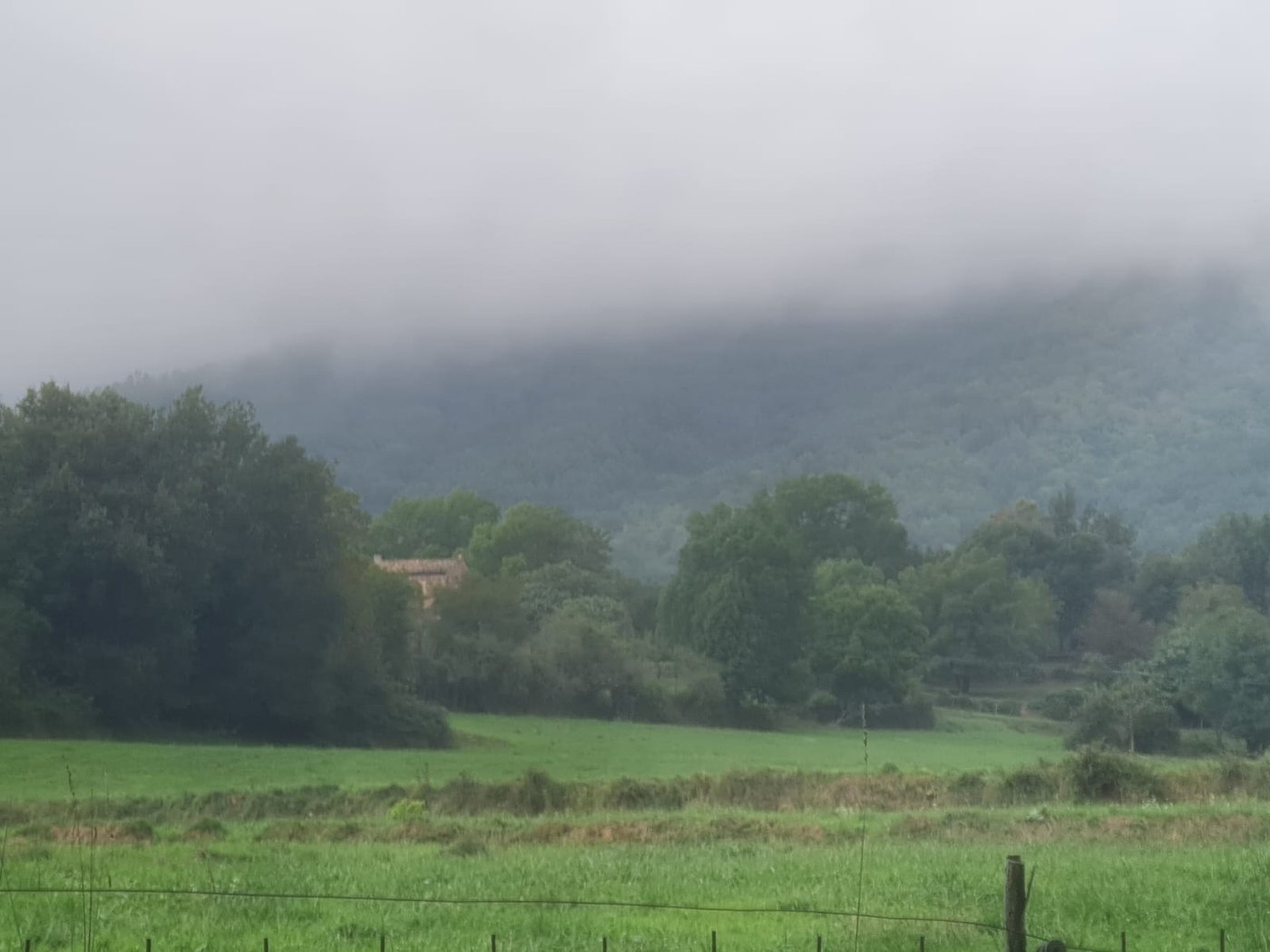 The Pradell farmhouse seen from the El Pati track, in Borredà, with the misty range behind