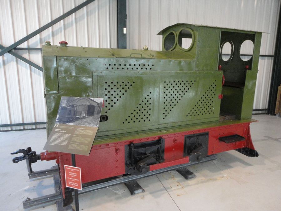 Small green and red industrial locomotive on display in the Tren del Ciment museum