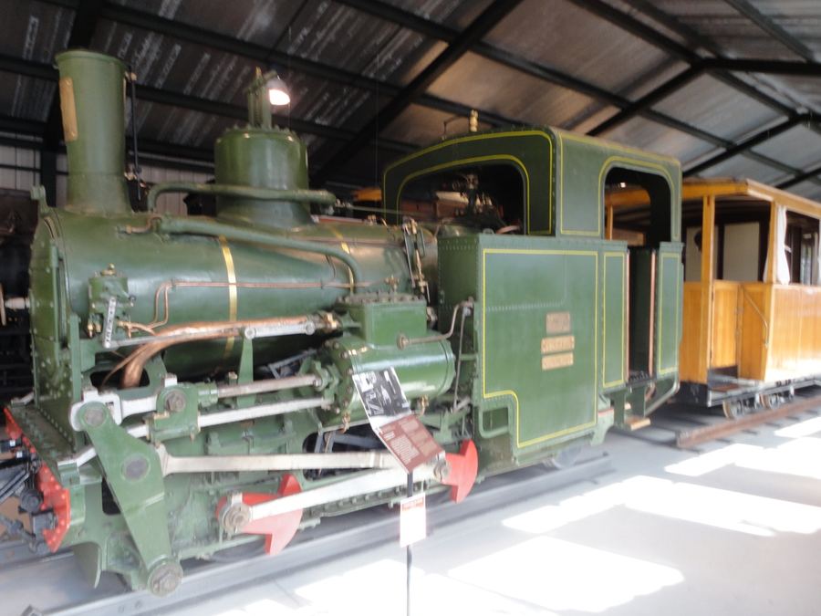 Restored green steam locomotive with a wooden carriage behind it, Tren del Ciment museum