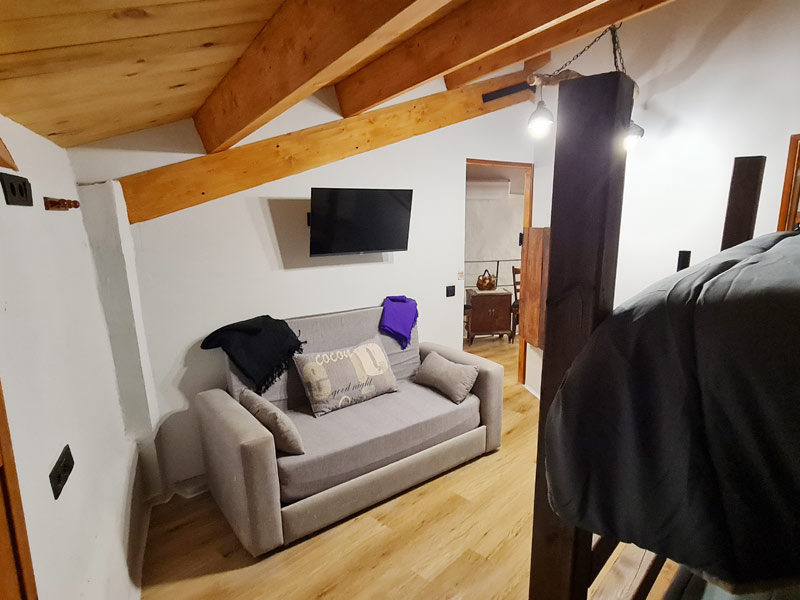 Tríplex Cal Barraqué de Dalt en Borredà - sofá cama y televisor de la habitación 2 de la buhardilla
