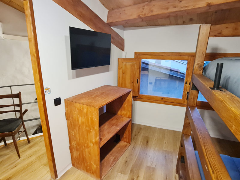 Tríplex Cal Barraqué de Dalt en Borredà - televisor, mueble y ventana de la habitación 1 de la buhardilla
